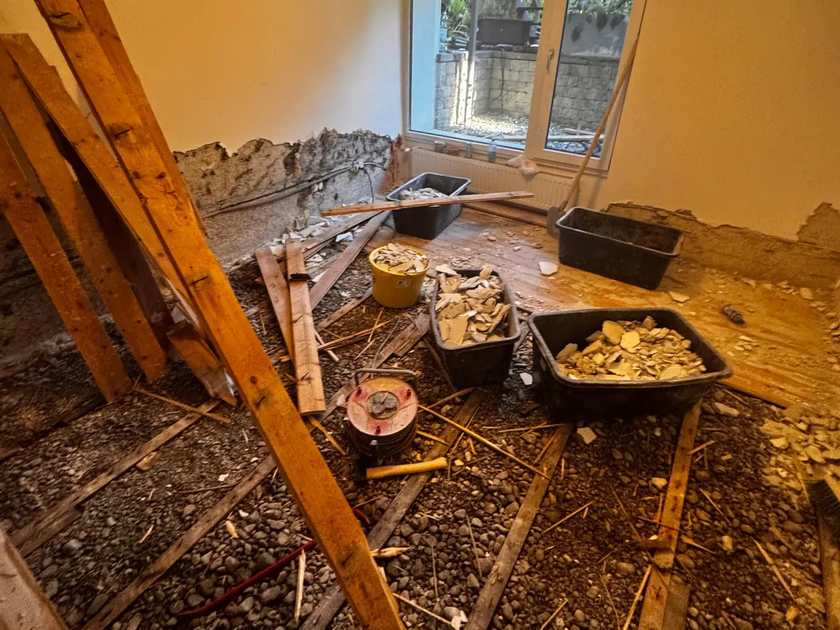 Rückbau von Holzboden und Unterkonstruktion im Kellerraum in Innsbruck-Hötting, Putz im Sockel abgeschlagen