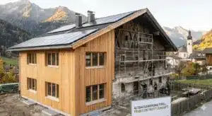 Altbausanierung in Tirol: Vorher-Nachher-Vergleich eines traditionellen Hauses mit energetischer Sanierung und neuen Fenstern vor Bergkulisse.